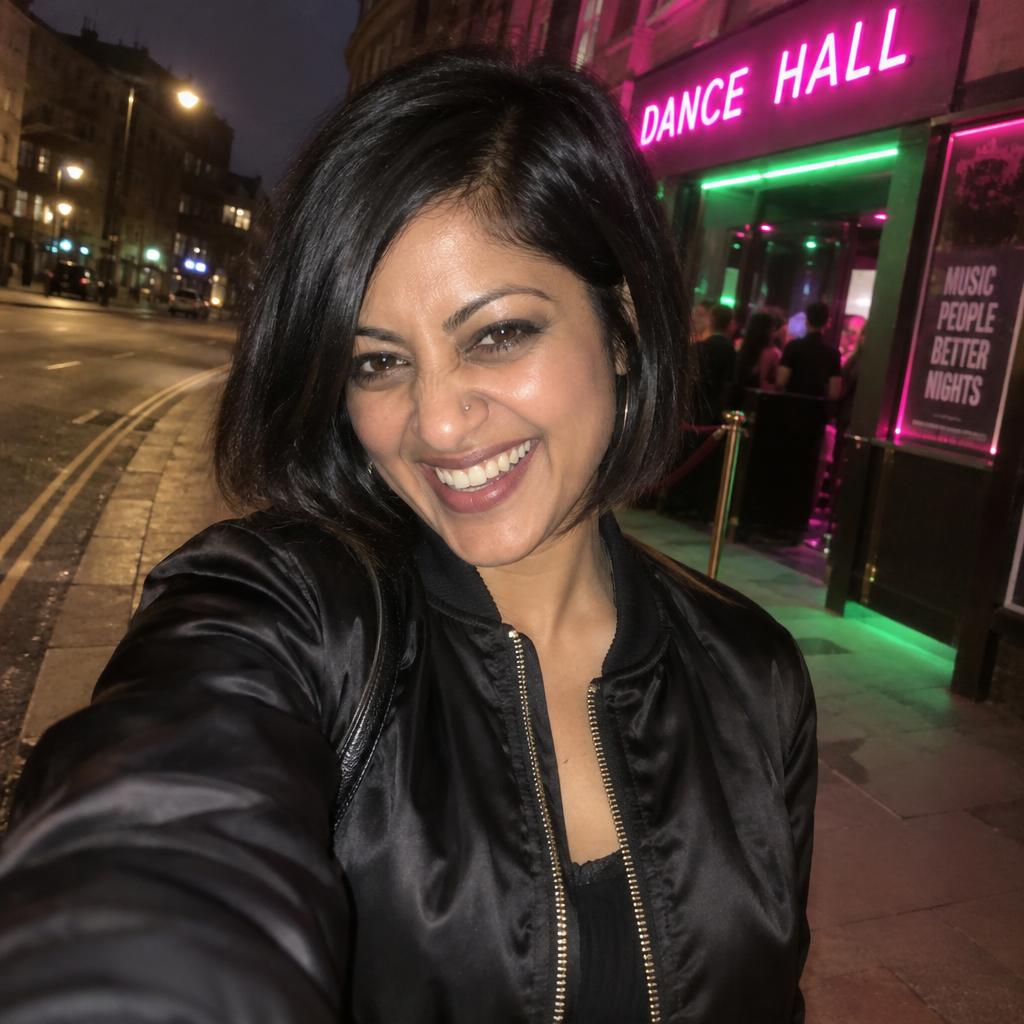 Fisheye Night-Out Snapshot: Arm’s-length close-up outside a neon-lit dance hall, caught mid-laugh with her chin tucked and a black satin bomber zipped halfway up.