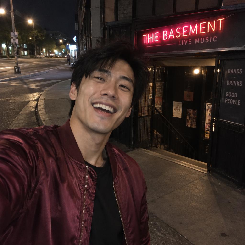 Fisheye Night-Out Snapshot: A slightly tilted, arm’s-length selfie outside a basement music venue, his laughing face filling one side of the frame and a burgundy satin…