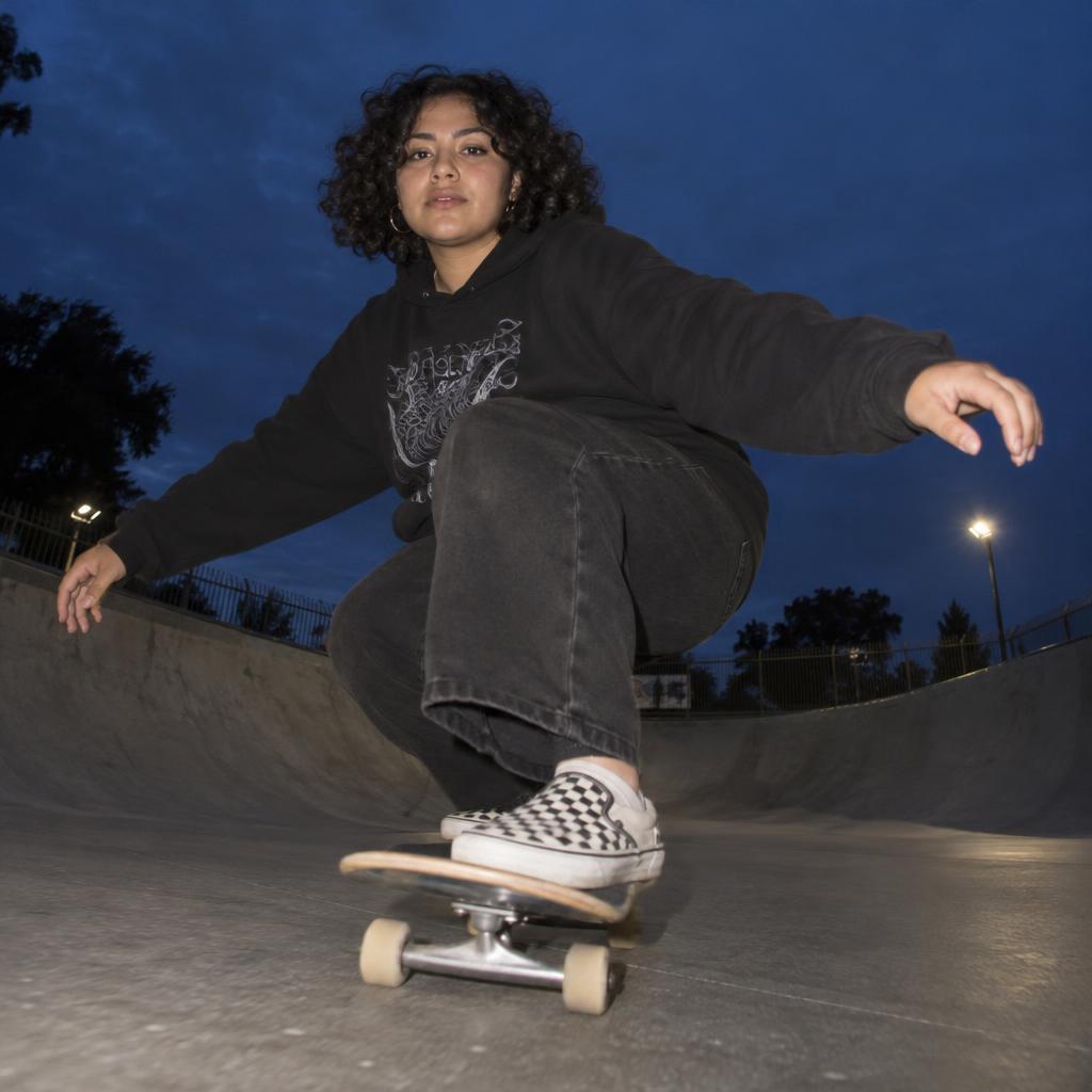 Skate-Park Wide-Angle: From ground level at the bowl’s flat bottom, capture one skater rolling toward the viewer, crouched low with arms spread for balance and…