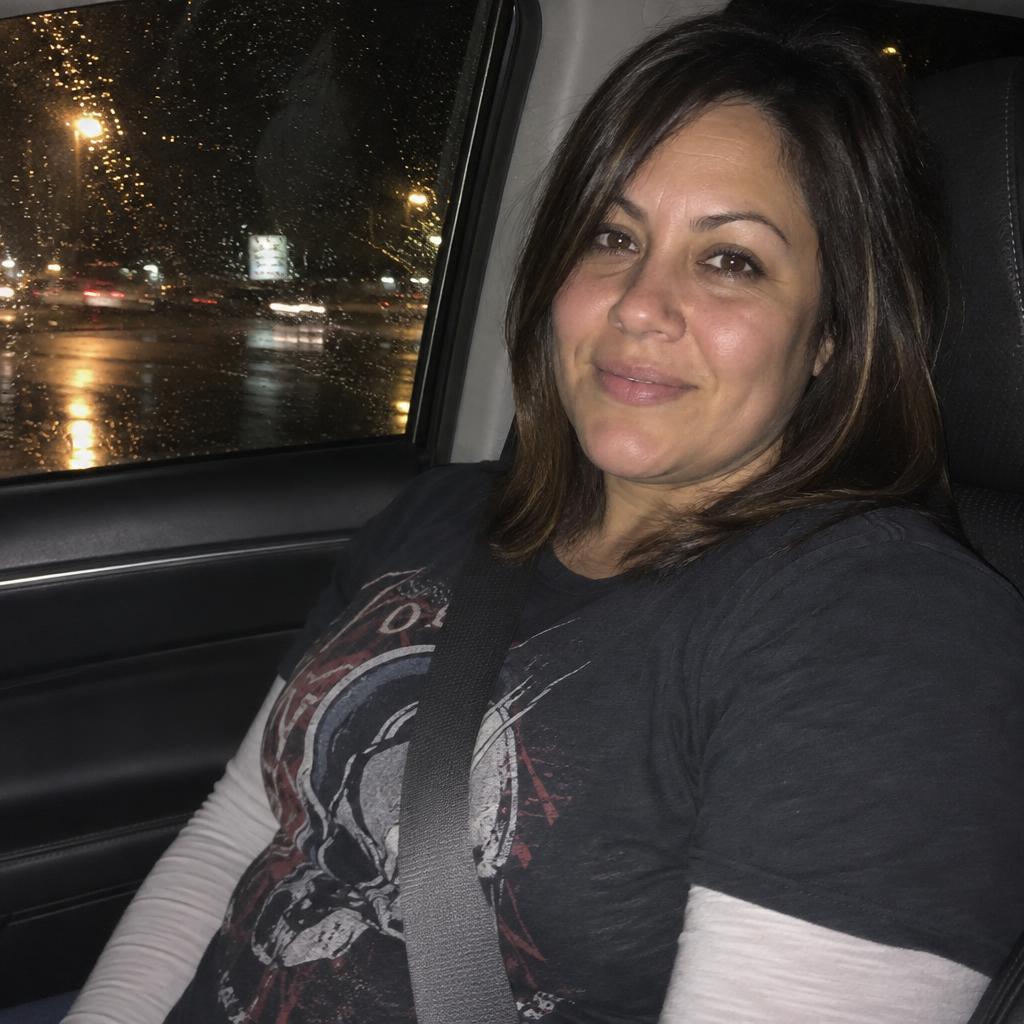 Car-Seat Point-and-Shoot: An eye-level passenger-seat portrait on a rainy night, framed from chest to head.